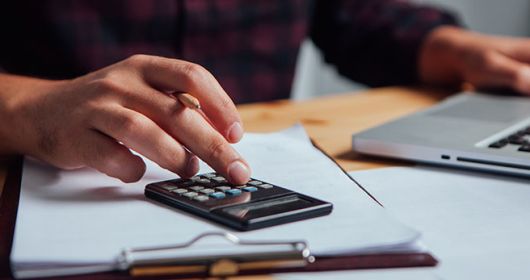 homme travaillant sur ordinateur et calculatrice