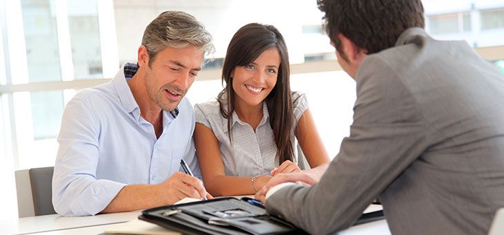 couple heureux signant un contrat en agence immobilière